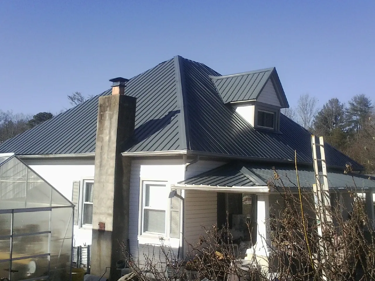 Dark blue standing seam metal roof on a white farmhouse with dormer — Slate & Tile Roof Repair by Roofing Brothers in Portage