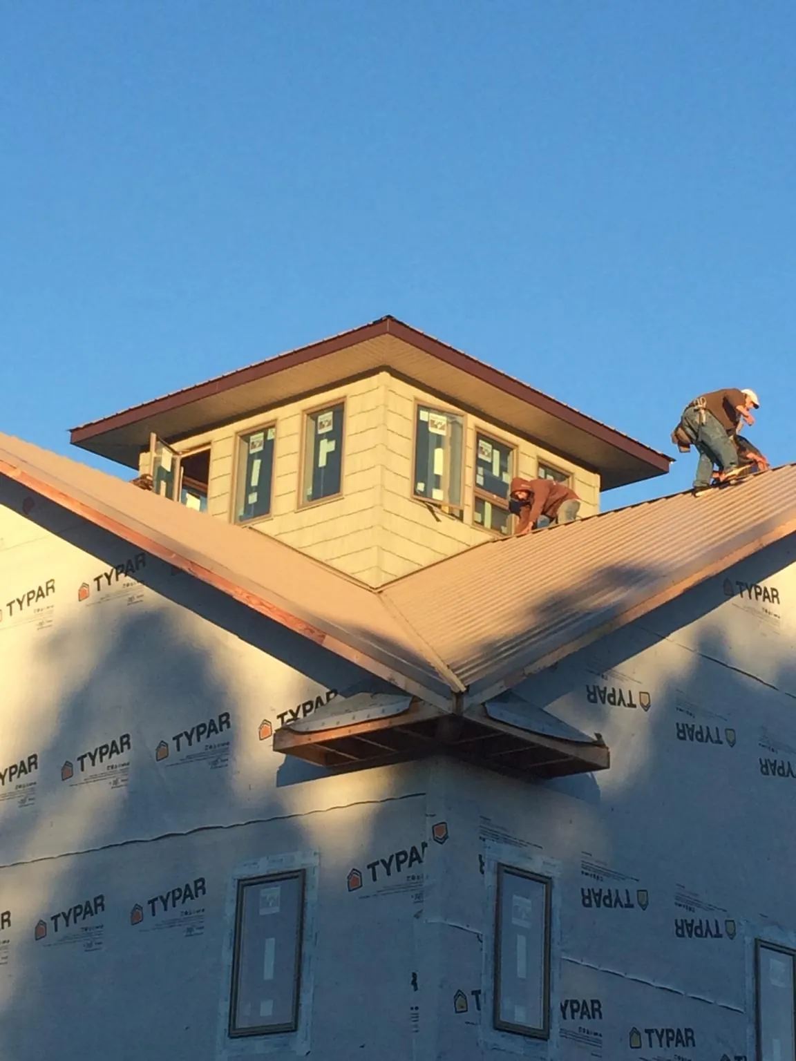 Roofers working around a rooftop cupola on a new metal roof at sunset — Roof Waterproofing in Portage by Roofing Brothers